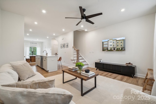 living room with ceiling fan, sink, and light hardwood / wood-style flooring