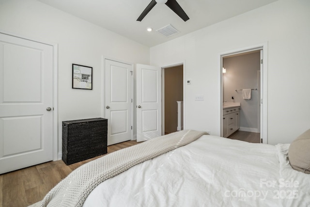 bedroom featuring ceiling fan, light hardwood / wood-style floors, and ensuite bath