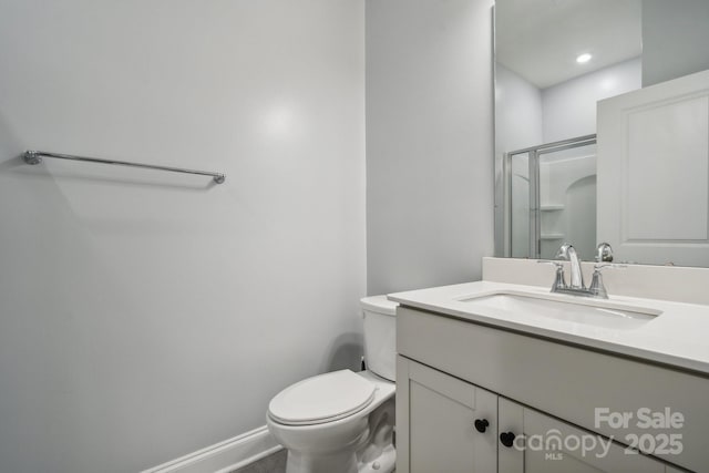 bathroom featuring toilet, a shower with shower door, and vanity