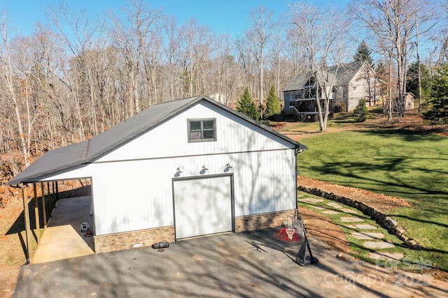 view of outdoor structure with a carport, a garage, and a lawn