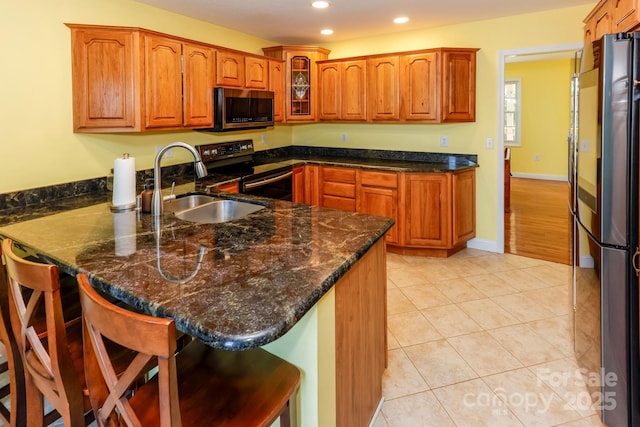 kitchen featuring kitchen peninsula, light tile patterned floors, a kitchen bar, and stainless steel appliances