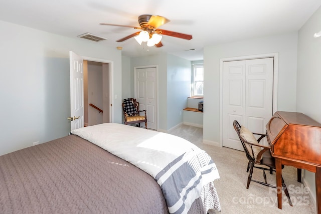 carpeted bedroom with ceiling fan and two closets