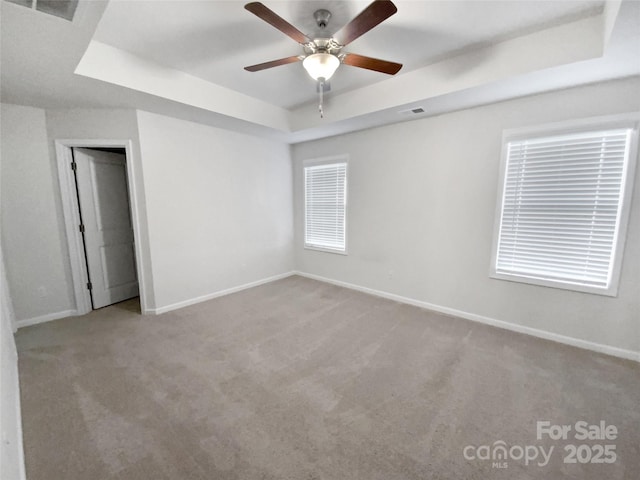 carpeted empty room with ceiling fan and a tray ceiling