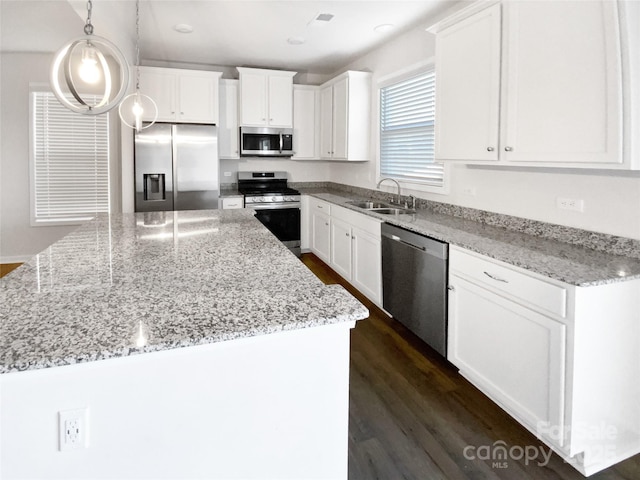 kitchen with decorative light fixtures, stainless steel appliances, white cabinetry, and sink