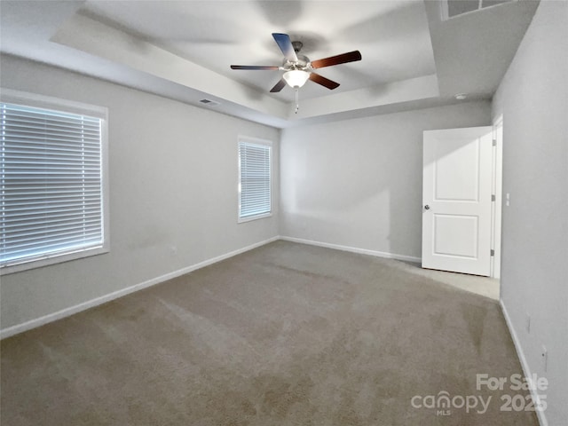 carpeted empty room featuring a tray ceiling and ceiling fan