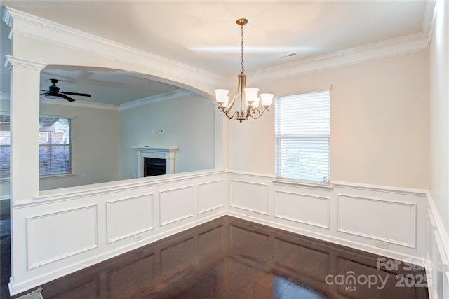 unfurnished dining area featuring ceiling fan with notable chandelier and crown molding