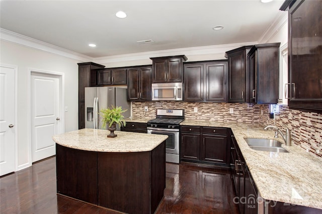 kitchen featuring light stone countertops, ornamental molding, stainless steel appliances, sink, and a kitchen island