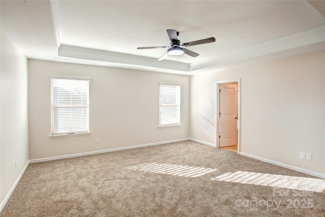 spare room featuring ceiling fan, a healthy amount of sunlight, a raised ceiling, and light colored carpet