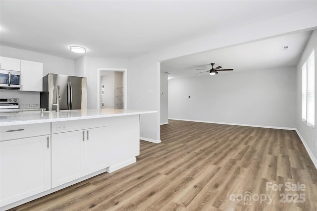 kitchen featuring white cabinets, appliances with stainless steel finishes, light stone countertops, and ceiling fan