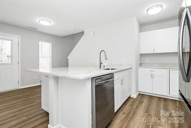 kitchen featuring light stone countertops, appliances with stainless steel finishes, sink, hardwood / wood-style flooring, and white cabinetry