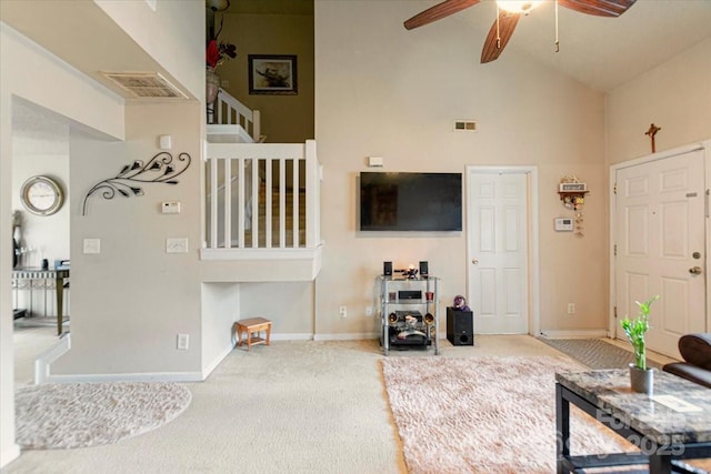 carpeted living room with ceiling fan and high vaulted ceiling