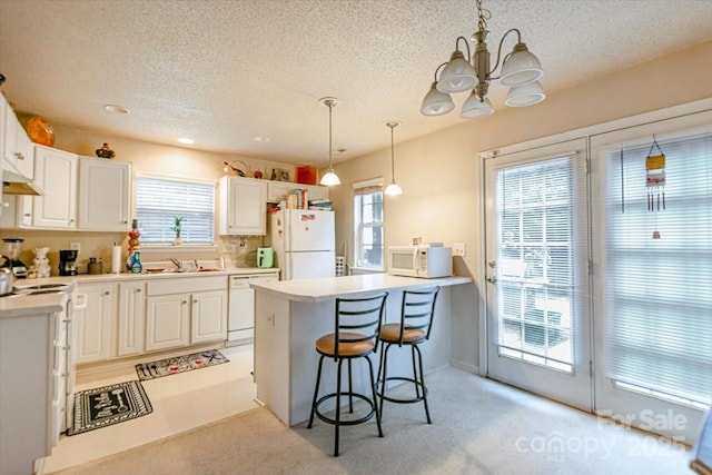 kitchen featuring white cabinets, a kitchen breakfast bar, and white appliances