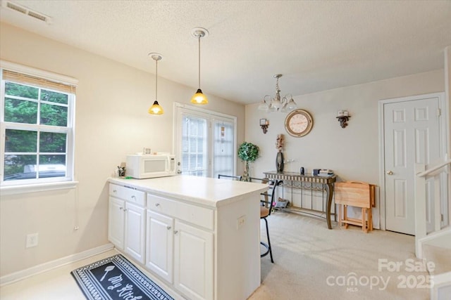 kitchen featuring kitchen peninsula, white cabinetry, hanging light fixtures, and an inviting chandelier