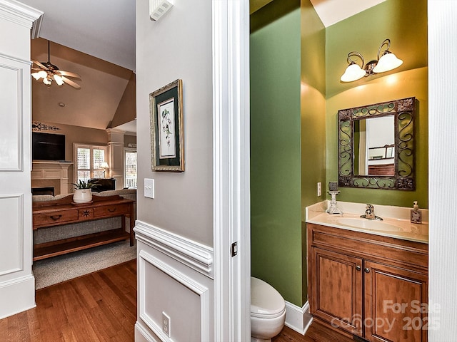 bathroom with vanity, vaulted ceiling, ceiling fan, hardwood / wood-style flooring, and toilet