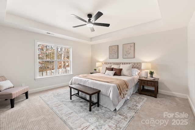 bedroom featuring a raised ceiling, ceiling fan, and light colored carpet