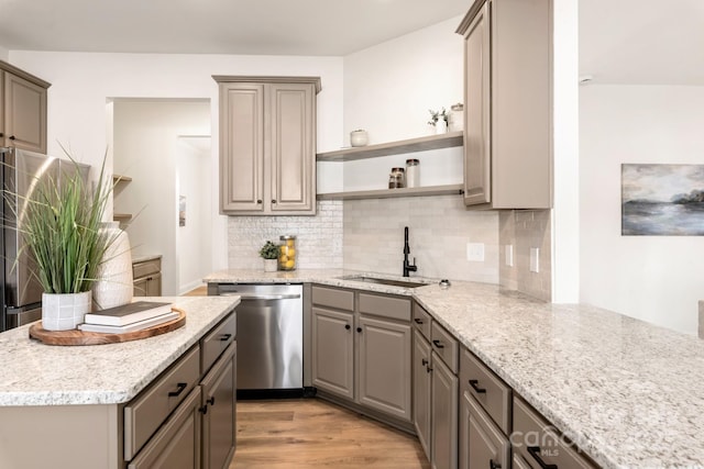 kitchen featuring dishwasher, backsplash, sink, light stone countertops, and light wood-type flooring