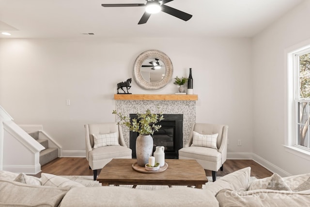 living room featuring hardwood / wood-style flooring, ceiling fan, and a tile fireplace