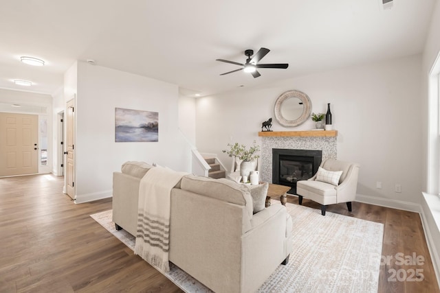 living room featuring a tiled fireplace, ceiling fan, and wood-type flooring