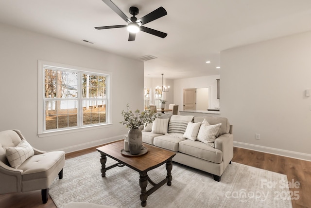 living room with ceiling fan with notable chandelier and light hardwood / wood-style floors