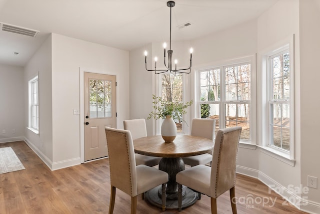 dining room featuring an inviting chandelier, a wealth of natural light, and light hardwood / wood-style flooring