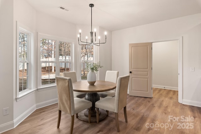 dining room with plenty of natural light, light hardwood / wood-style flooring, and a chandelier