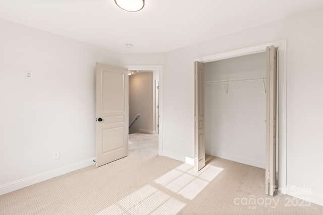 unfurnished bedroom featuring light carpet and a closet