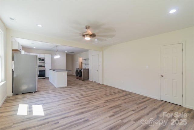 unfurnished living room featuring light hardwood / wood-style flooring, washer and clothes dryer, and ceiling fan