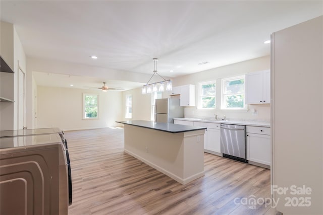 kitchen featuring a center island, hanging light fixtures, ceiling fan, appliances with stainless steel finishes, and white cabinetry