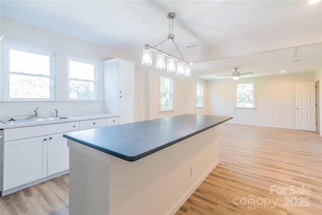 kitchen with sink, pendant lighting, a center island, light hardwood / wood-style floors, and white cabinetry