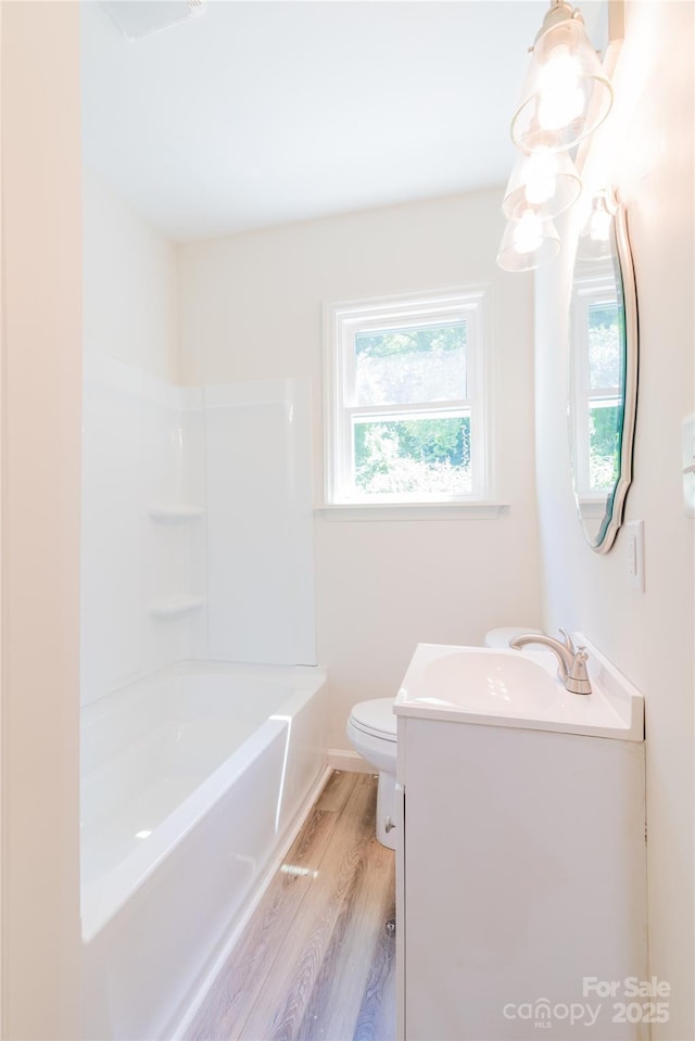 full bathroom with shower / bath combination, vanity, wood-type flooring, and toilet