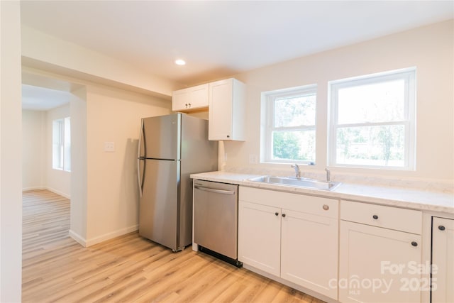 kitchen with sink, white cabinetry, stainless steel appliances, and light hardwood / wood-style flooring