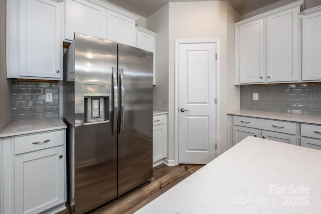 kitchen featuring white cabinetry, light stone counters, decorative backsplash, stainless steel fridge with ice dispenser, and dark wood-type flooring