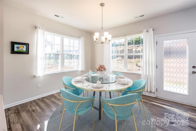 dining room featuring a wealth of natural light, a notable chandelier, and dark wood-type flooring