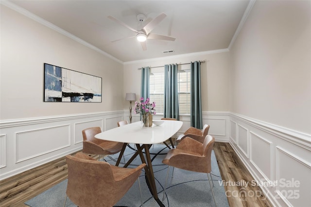 dining area featuring dark hardwood / wood-style flooring, ornamental molding, and ceiling fan