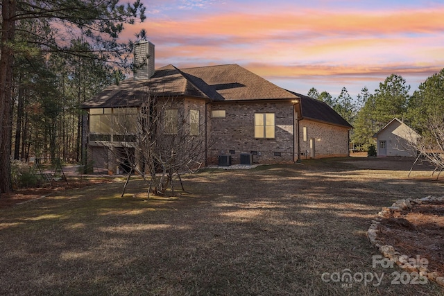 property exterior at dusk with a yard and central AC unit