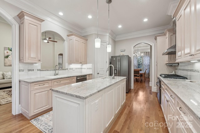 kitchen with sink, stainless steel appliances, tasteful backsplash, decorative light fixtures, and a center island with sink