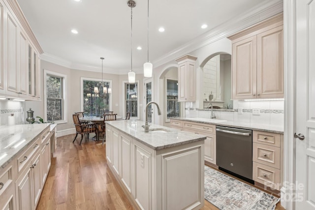 kitchen with sink, stainless steel dishwasher, hanging light fixtures, and an island with sink