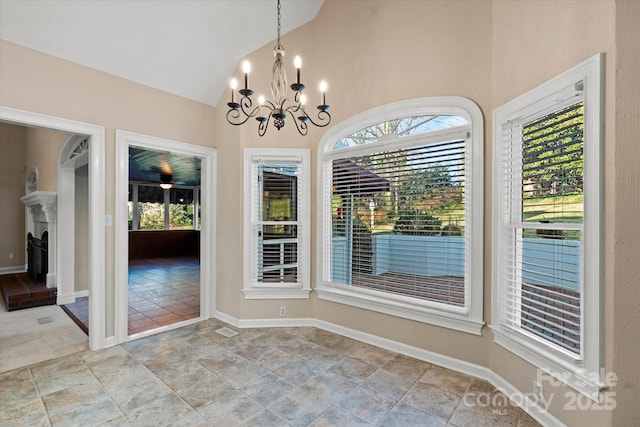 unfurnished dining area featuring a healthy amount of sunlight, vaulted ceiling, and an inviting chandelier