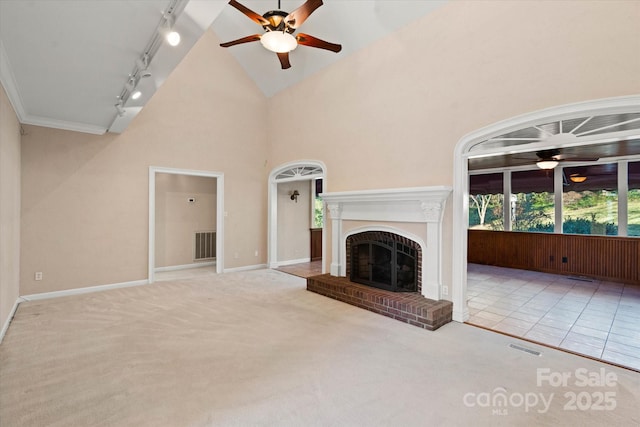 unfurnished living room featuring ceiling fan, rail lighting, light carpet, and a fireplace