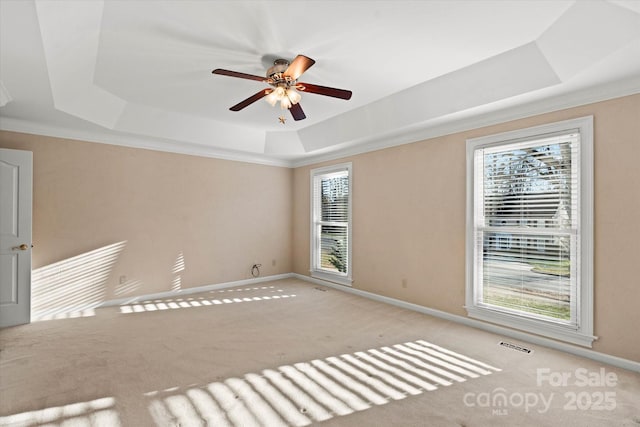 spare room with ceiling fan, crown molding, light colored carpet, and a tray ceiling