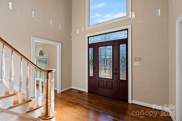 entryway featuring dark wood-type flooring and a towering ceiling