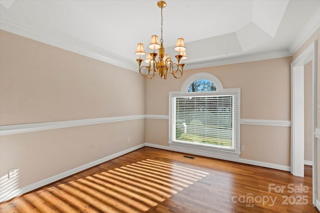 interior space with a chandelier, ornamental molding, wood-type flooring, and a tray ceiling