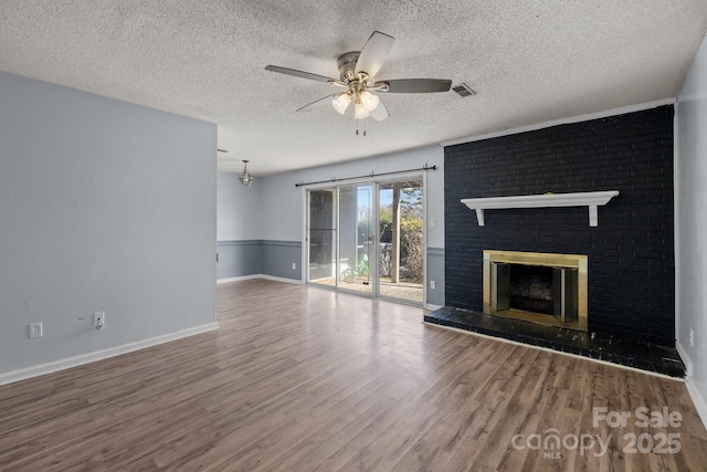 unfurnished living room with hardwood / wood-style floors, a textured ceiling, a brick fireplace, and ceiling fan