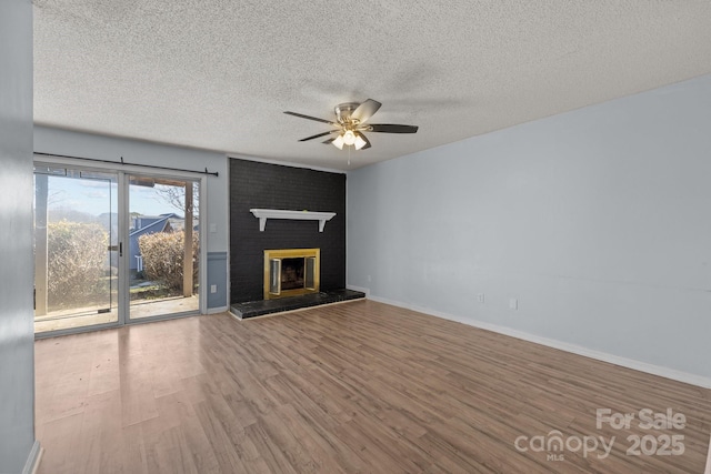 unfurnished living room with ceiling fan, a fireplace, hardwood / wood-style floors, and a textured ceiling