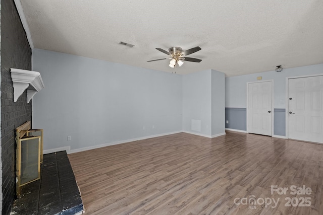 unfurnished living room with a fireplace, a textured ceiling, hardwood / wood-style flooring, and ceiling fan