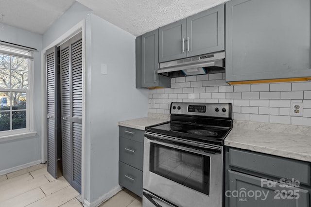 kitchen featuring gray cabinetry, stainless steel electric range oven, tasteful backsplash, a textured ceiling, and light tile patterned floors