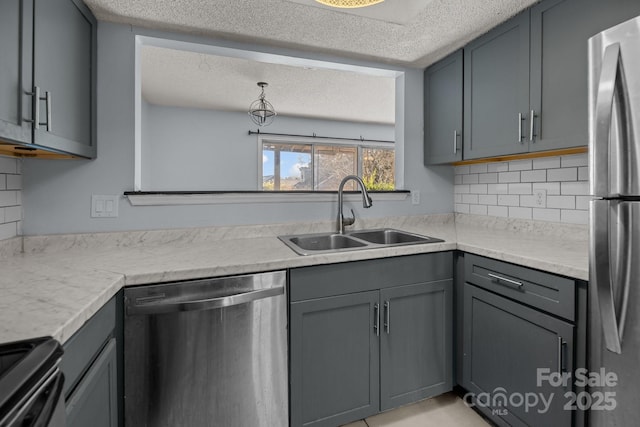 kitchen with sink, backsplash, a textured ceiling, gray cabinets, and appliances with stainless steel finishes