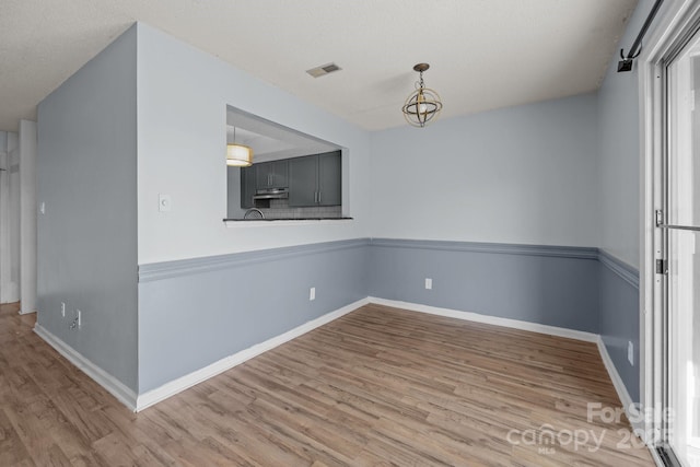 unfurnished room with a chandelier and wood-type flooring