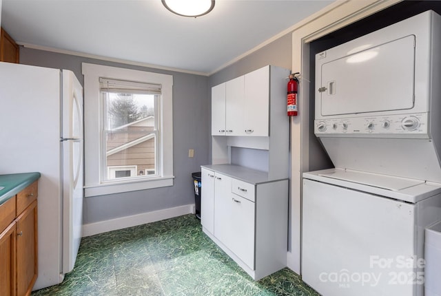 washroom featuring ornamental molding and stacked washer and clothes dryer