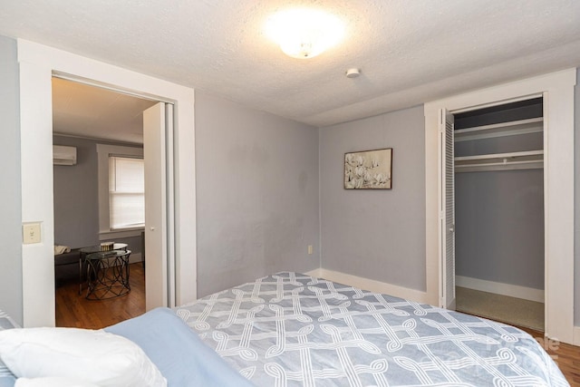 bedroom featuring hardwood / wood-style flooring, a wall unit AC, a closet, and a textured ceiling